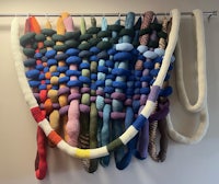 a colorful woven wall hanging hanging on a wall