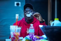 a man in a red hoodie smoking a cigarette