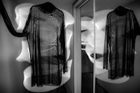 a black and white photo of a dress hanging in a mirror
