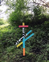 a colorful cross in the middle of a wooded area