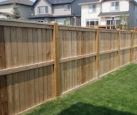 a wooden fence in a backyard with green grass
