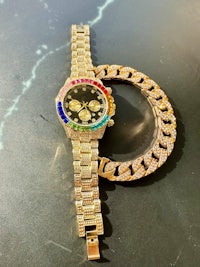a gold watch with a rainbow bezel and a chain