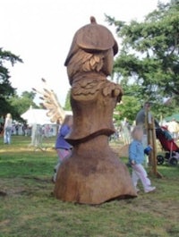 a wooden sculpture of a chess piece in a park