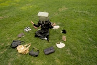 a man sitting on the grass with bags around him
