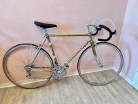 a gold bicycle leaning against a pink wall