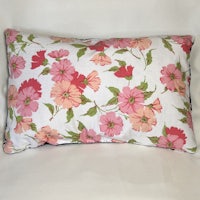 a pink and green floral pillow on a white background