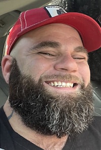 a man with a beard smiling in a car