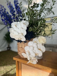 white orchids in a wicker basket on top of a wooden table