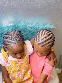two little girls with braided hair sitting next to each other