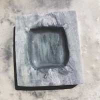 a square stone ashtray on a concrete surface