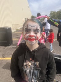 a young girl with clown makeup on her face