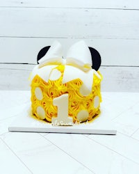 a yellow and white minnie mouse cake with a white bow