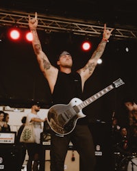 a man with tattoos playing a guitar on stage