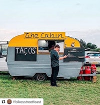a man standing next to a food truck in a field