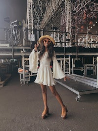 a woman in a white dress posing in front of a stage