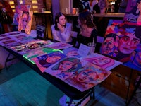 a group of people sitting at a table with paintings on it