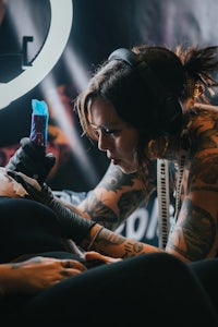 a woman is getting tattooed by a tattoo artist