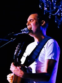 a man singing into a microphone while playing an acoustic guitar