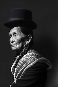 a black and white photo of an old woman wearing a hat