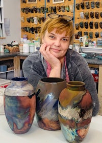 three vases in a studio with a woman posing in front of them