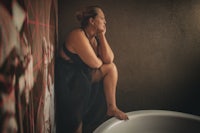 a woman sitting in a bathtub looking at a wall