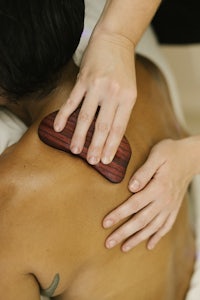 a woman getting a back massage with a wooden board