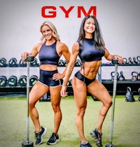 two women posing in front of a gym