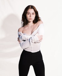 a young woman posing in black pants and a white top
