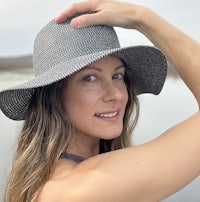 a woman is posing in a hat near a body of water