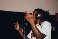 a man with dreadlocks holding a microphone in a recording studio