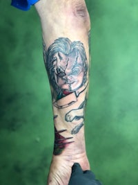 a tattoo of a clown on a person's forearm