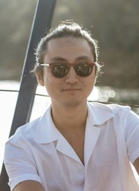 a man wearing sunglasses and a white shirt sitting on a boat