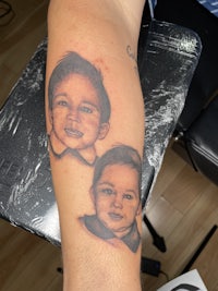 a tattoo of two faces on the arm of a man