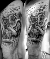 a black and white tattoo of a man with an angel on his thigh
