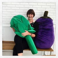 a woman sitting on a bench holding a purple and green bean bag