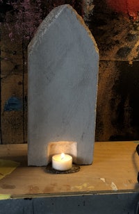 a candle is sitting on a table next to a piece of wood