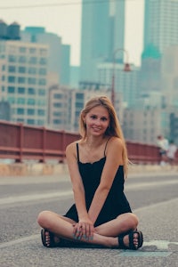 a young woman sitting on the ground in front of a city
