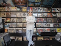 a man standing in front of a wall of records