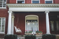 a red brick house with a swing on the porch
