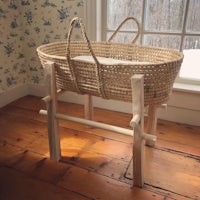 a wicker basket on a wooden stand in front of a window