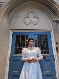a woman in a white wedding dress standing in front of a blue door
