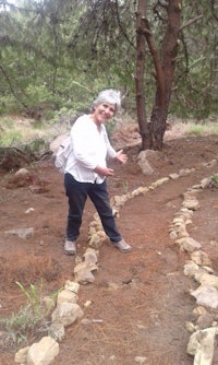 a woman standing in a wooded area with rocks