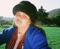 a woman in a plaid hat sitting in a field