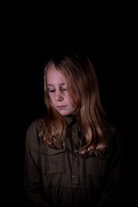 a young girl in a green shirt is standing in front of a black background