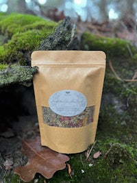a bag of herbal tea sitting on a log in the woods