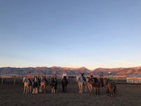 a group of people on horses at sunset