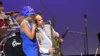 a woman in a blue dress is holding a saxophone