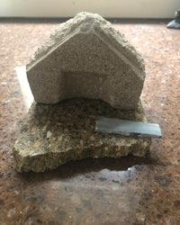 a model of a house on top of a piece of rock