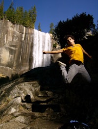 a man is jumping in front of a waterfall