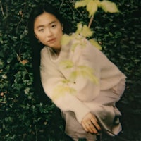 a young asian woman crouching next to a tree